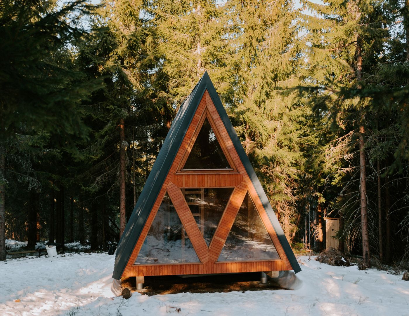 Refugio de madera en forma de A en un bosque nevado